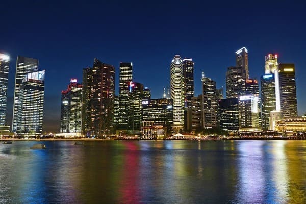 fotografía de ciudad de negocios de noche. Altos edificios iluminados al borde del mar, simbolizando la inversión exterior